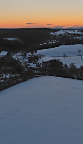 Aerial view of Pocono Mountains at sunset with snow-covered fields