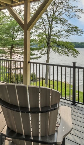 Lakefront deck with Adirondack chairs overlooking calm water and trees