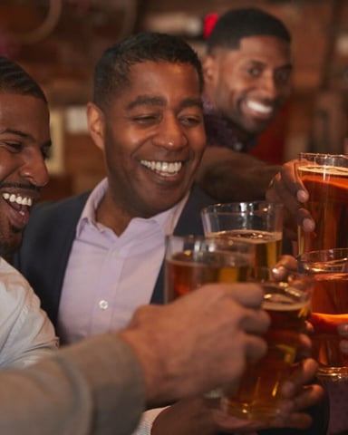 Group of men toasting with beer glasses at a bar