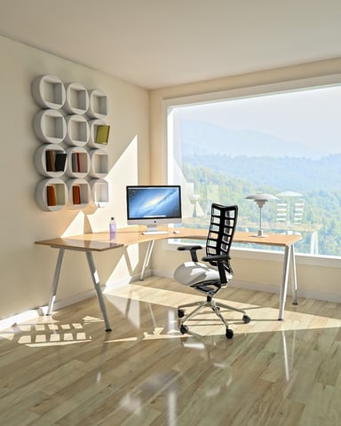 Home office with desk, computer, and black chair overlooking forested mountains through large window