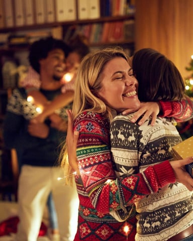 Family gathering by a Christmas tree in a warm living room