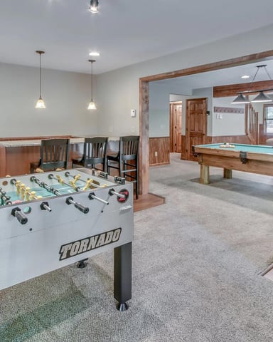 Finished basement game room with foosball table, pool table, air hockey, and dining area with wood accents