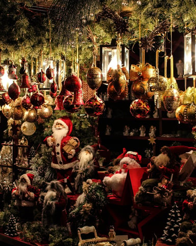 Elaborate Christmas window display with hanging ornaments, garland, Santa figures, and miniature trees under warm lighting