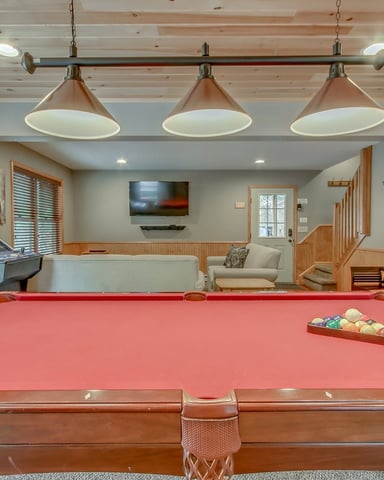 Game room with red pool table, arcade machine, pendant lights, TV, and wood-paneled walls