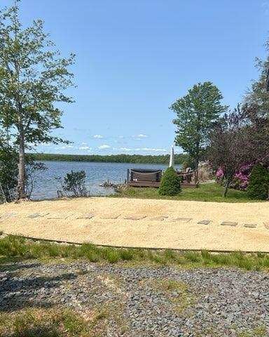 Waterfront property with sandy beach, wooden deck, and lake view on clear day