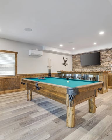 Recreation room with pool table, arcade game, wall-mounted TV, and stone accent wall