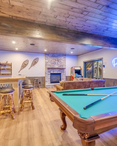 Recreation room with pool table, bar seating, fireplace, TV, and neon sign lighting