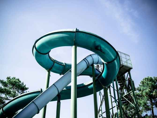 Teal spiral water slide towering against a blue sky at a waterpark