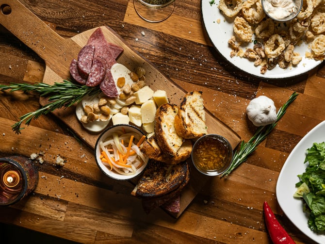Charcuterie board with meats, cheeses, and grilled bread on a rustic wooden table