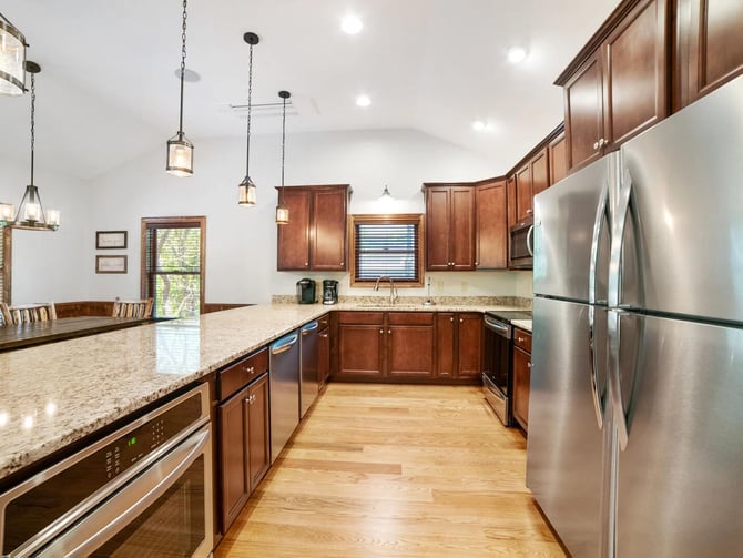 Modern kitchen with dark wood cabinetry, granite countertops, stainless steel appliances, and pendant lighting over island