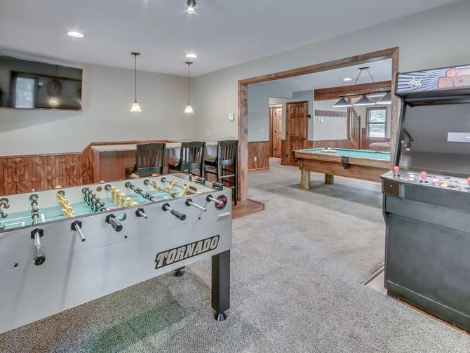 Finished basement game room with foosball table, pool table, air hockey, and dining area with wood accents